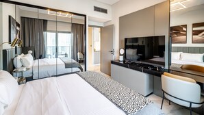 Een moderne hotelkamer met een groot bed, een bureau met een flatscreen televisie, een stoel en een grote spiegel.