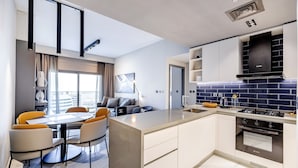 Een moderne keuken met een centraal kookeiland, inbouwapparatuur en een eethoek met een tafel en stoelen.