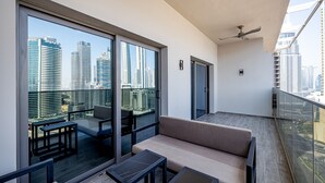 Een modern balkon met een bank, twee tafels en uitzicht op de stad.