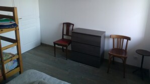 A room with a bunk bed, a desk with a chair, a dresser, and a television on the wall. - Ecological country house (Èvres)