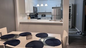 A modern kitchen with white cabinets, stainless steel appliances, and pendant lighting. - Rehoboth Beach Condo 1 mile to the beach and Boardwalk w/ pool! Sleeps 6 (Rehoboth Beach)