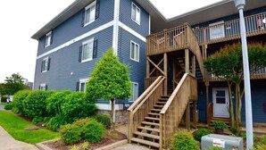 A two-story building with a wooden staircase leading to a balcony. - Rehoboth Beach Condo 1 mile to the beach and Boardwalk w/ pool! Sleeps 6 (Rehoboth Beach)