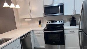 A modern kitchen with white cabinets, stainless steel appliances, and a wooden floor. - Rehoboth Beach Condo 1 mile to the beach and Boardwalk w/ pool! Sleeps 6 (Rehoboth Beach)
