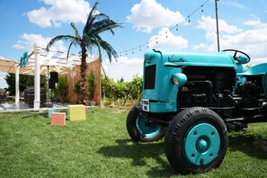 A vintage tractor parked on grass with a clear sky and palm trees in the background. - The Rest Port Village Hotel (Havsa)