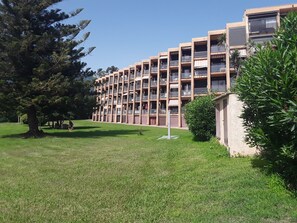 A multi-story building with balconies and a grassy area in front. - Studio les pieds dans, santa lucia (Santa-Lucia-di-Moriani)