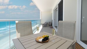 Een balkon met een eettafel, met uitzicht op de oceaan.
