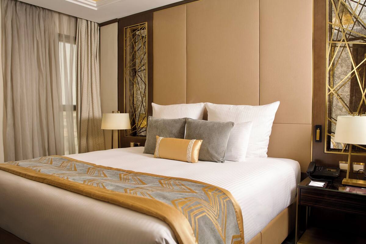 A hotel room with a large bed, two bedside tables, a lamp, and a decorative wall panel.
