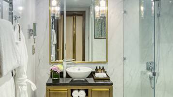 Un baño moderno con lavamanos de mármol, cabina de ducha de vidrio y tocador de madera.