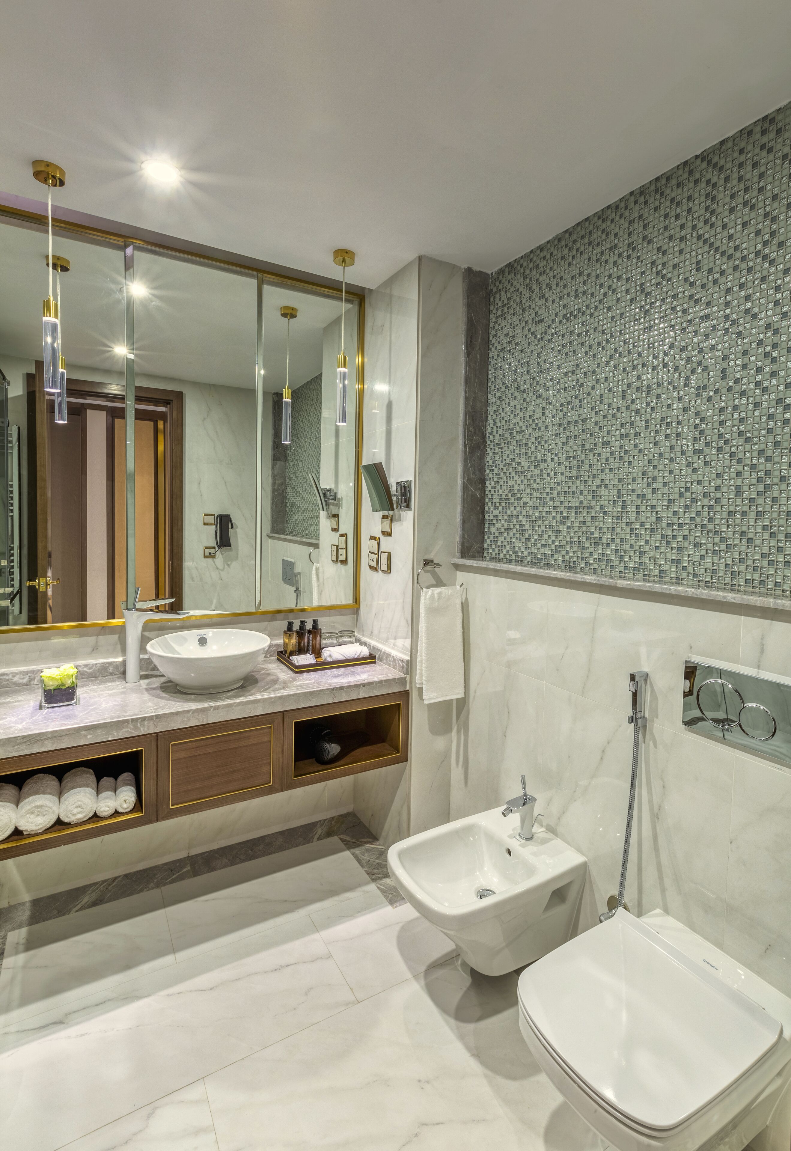 Een moderne badkamer met een grote spiegel, een wastafel, een toilet en een hygiëneschuimer.