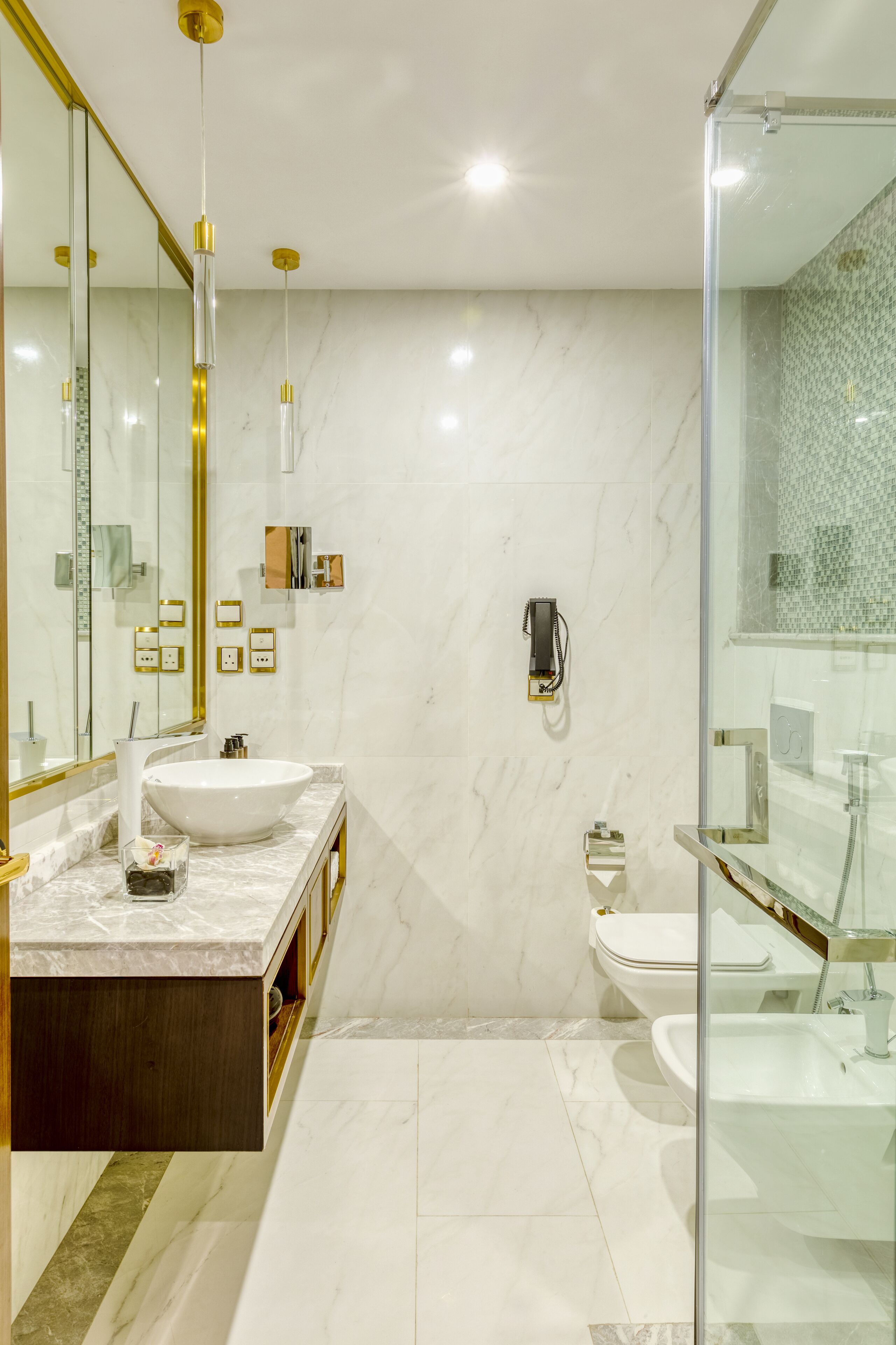 Een moderne badkamer met een grote spiegel, een wit wastafelmeubel, een douchecabine van glas en een toilet.