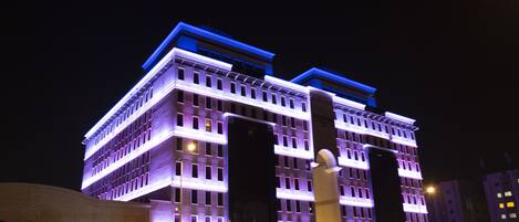 Ein mehrstöckiges Hotel mit moderner Fassade, beleuchtet in Lila und Blau.