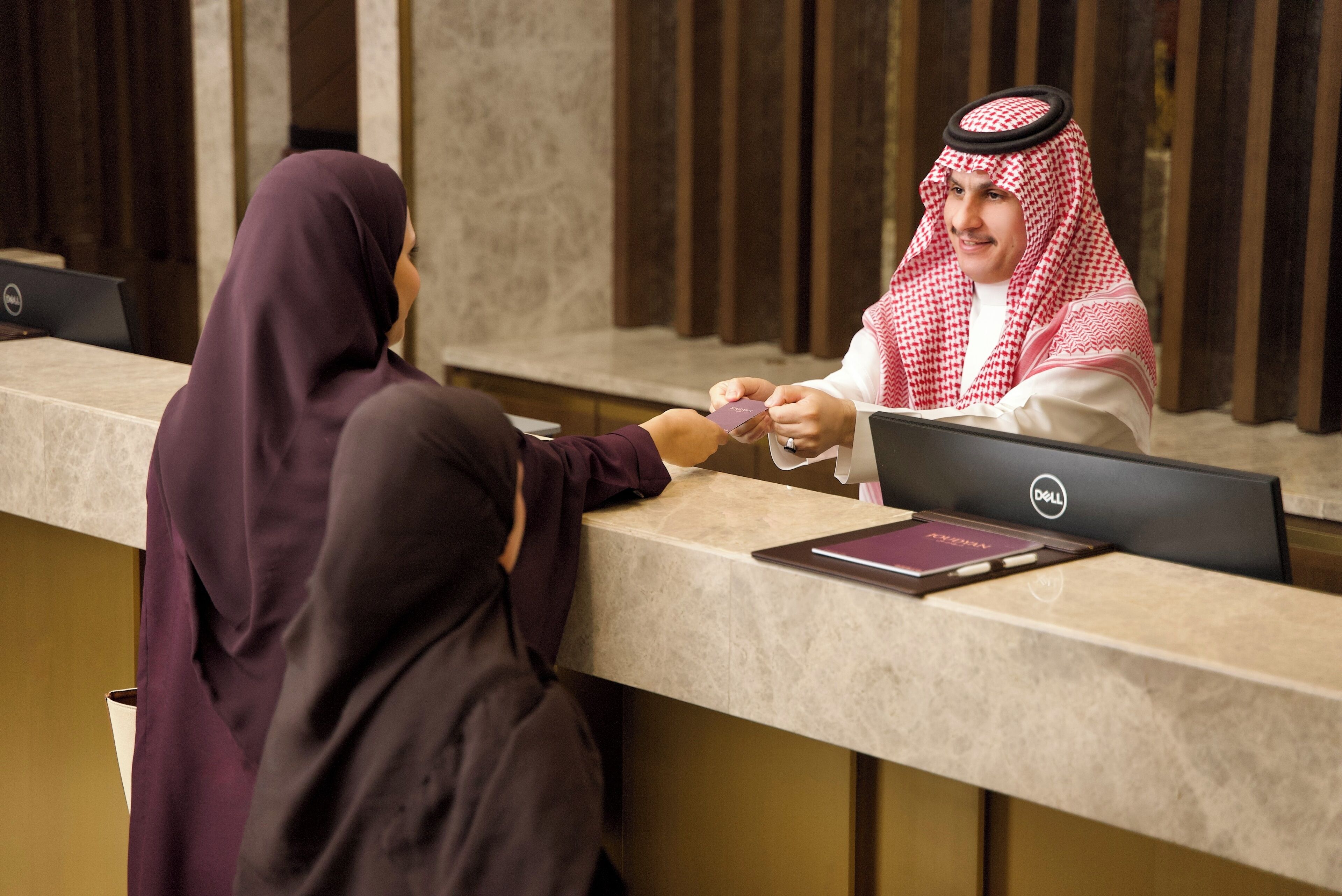A reception desk with a laptop and a passport.