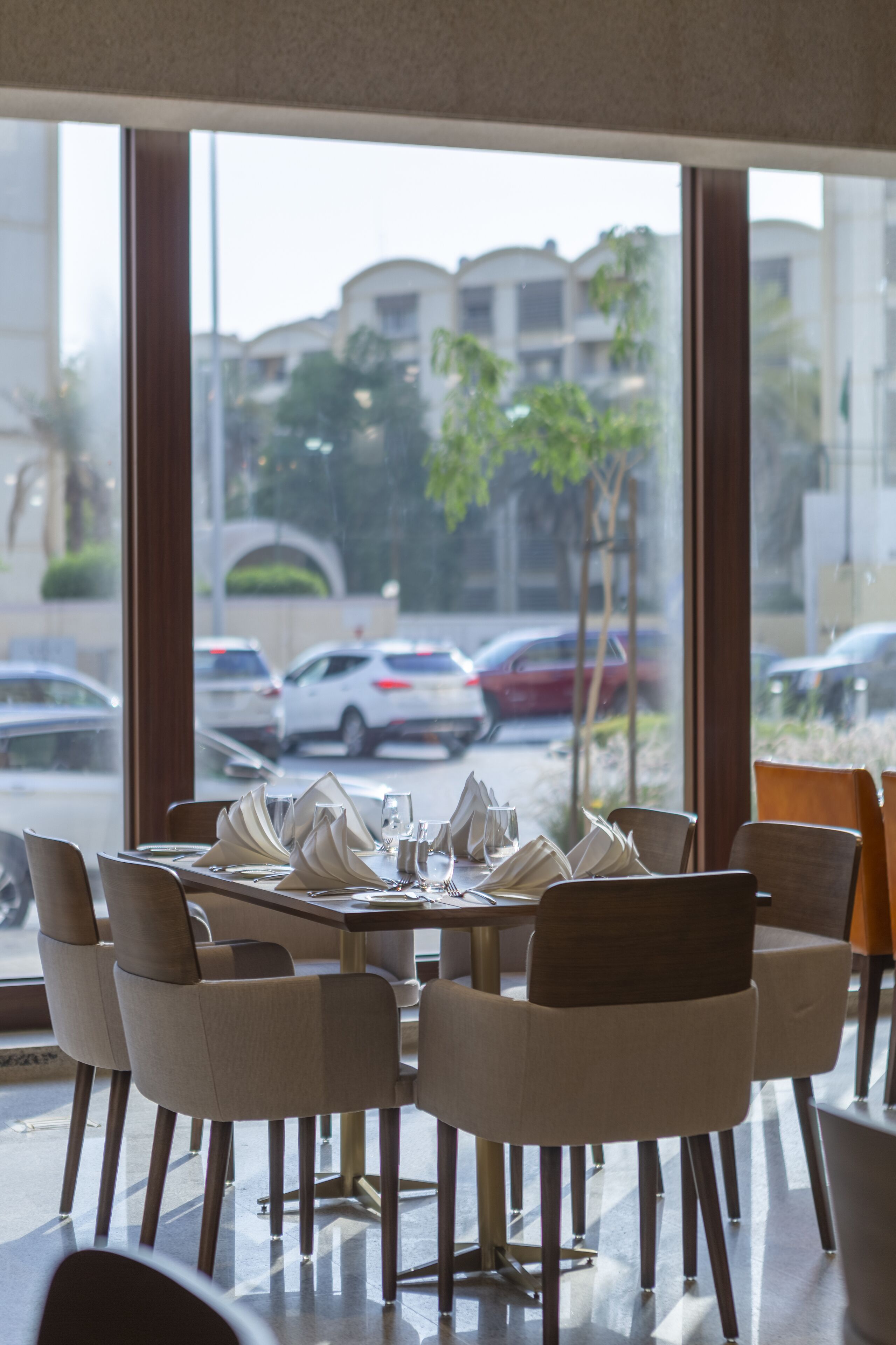 A restaurant with a view of parked cars and buildings outside.