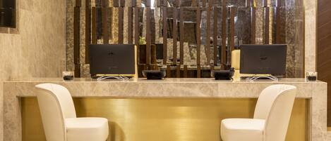 A reception desk with two chairs, a marble counter, and two laptops.