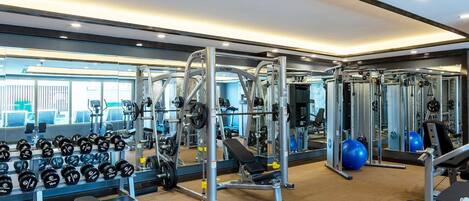 A modern gym with weightlifting equipment, exercise balls, and dumbbells.