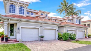 A two-story house with a red-tiled roof, numbered 5518, featuring a large garage and a well-maintained front yard with potted plants. - Casa Boho | Cape Harbour 3/2 Coach Home (Cape Coral)