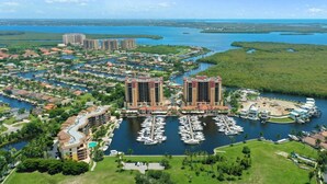 A coastal resort with two prominent buildings, a marina with numerous boats, and surrounding greenery. - Casa Boho | Cape Harbour 3/2 Coach Home (Cape Coral)