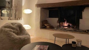 Una habitación acogedora con chimenea, un sillón mullido y una mesa con velas.