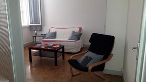 Una habitación pequeña y ordenada con una cama, una silla y una mesa.