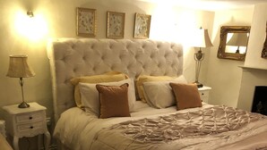A bedroom with a large bed, a nightstand, a lamp, and framed artwork on the wall. - Impeccable 3-bed 17th Century Luxury Cottage (Longhope)