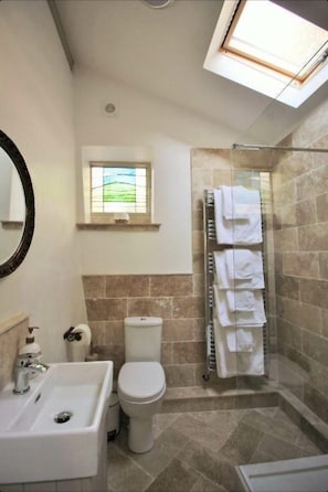 A bathroom with a shower, toilet, sink, and a window with a view.