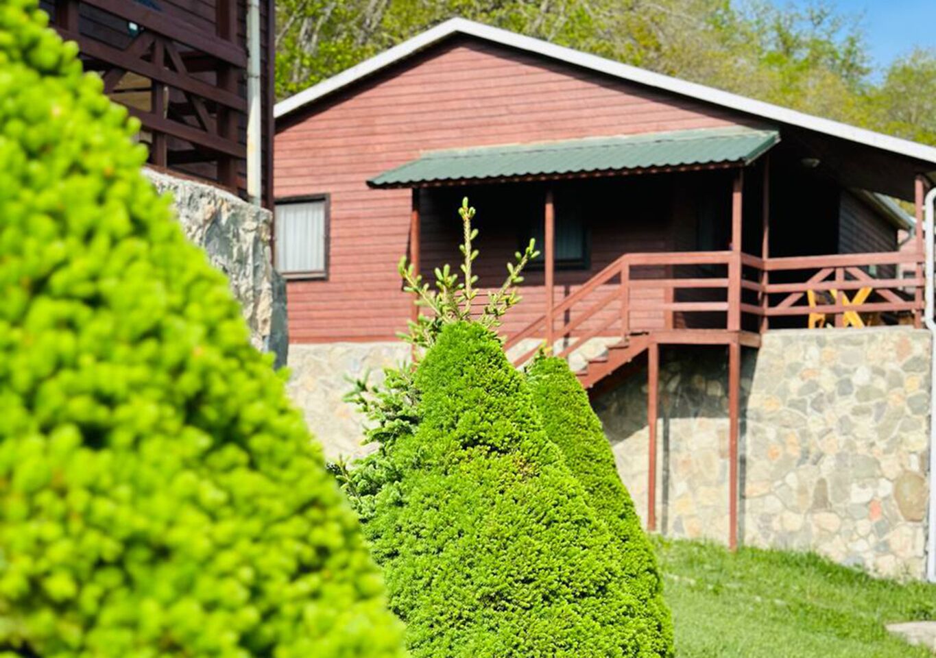 Un bâtiment rouge avec des fondations en pierre et une terrasse en bois.