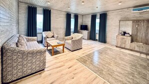 Un ampio soggiorno con soffitto in legno, un divano, un tavolino da caffè e una TV.
