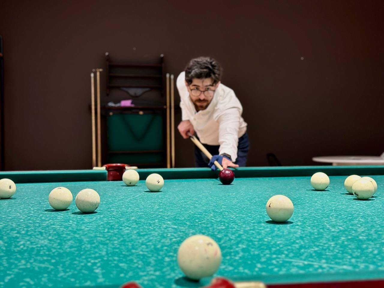 A pool table with balls and a cue stick.