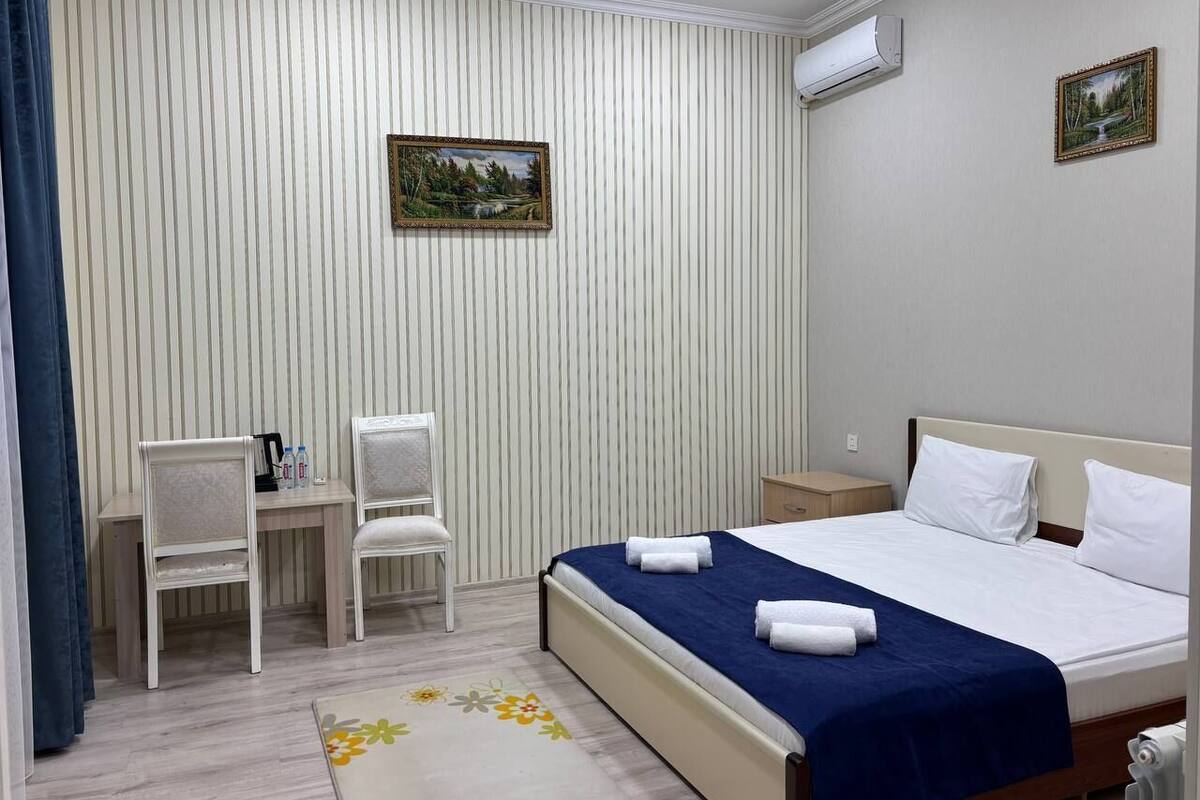 A hotel room with a bed, two chairs, a desk, and a small table.