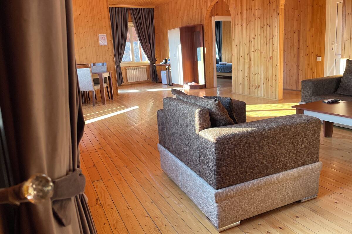 A cozy wooden interior with a sofa, a dining area, and a bed.