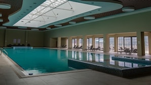 Una piscina interna con lucernario, poltrone relax e vista sulla città.