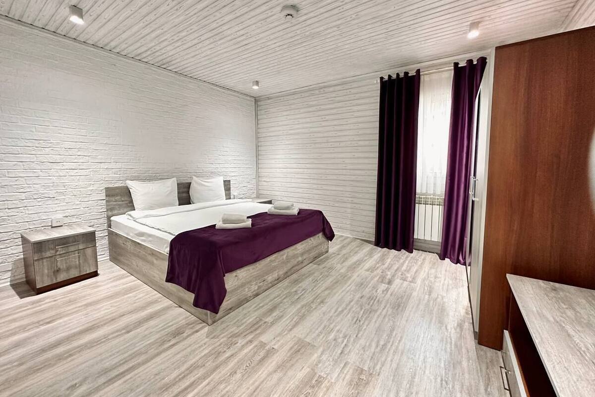 A modern bedroom with a wooden bed, a nightstand, and a wooden bench.