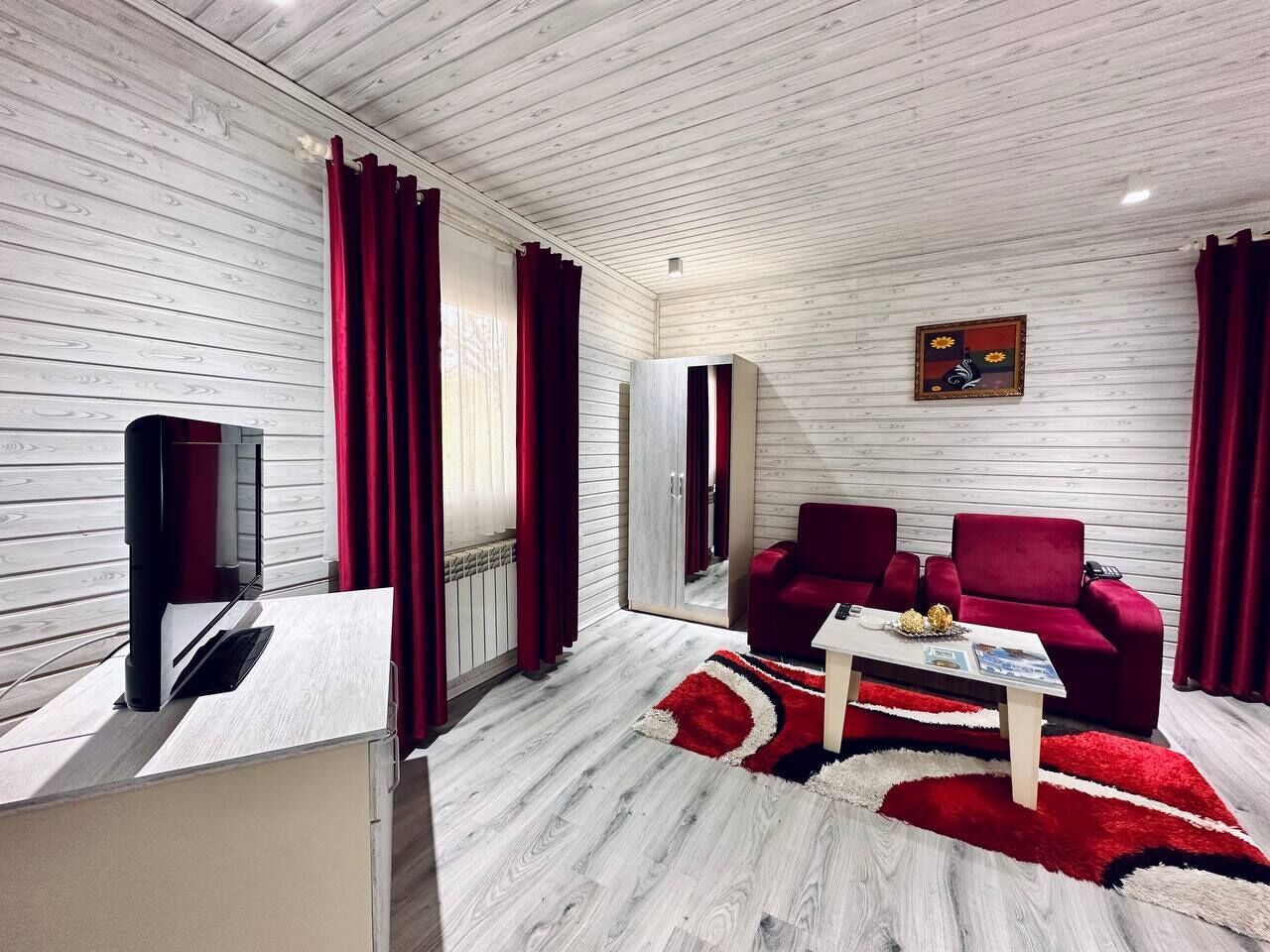 Una sala de estar moderna con un sofá rojo, una mesa de centro y un televisor sobre un mueble de madera.