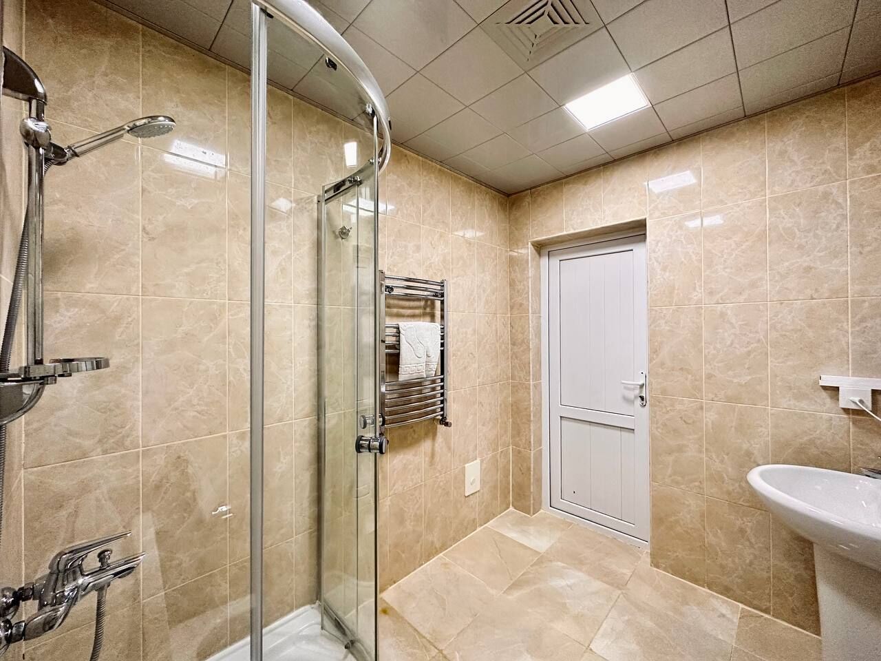 Une salle de bain moderne avec une douche à parois de verre, un lavabo et un porte-serviettes.