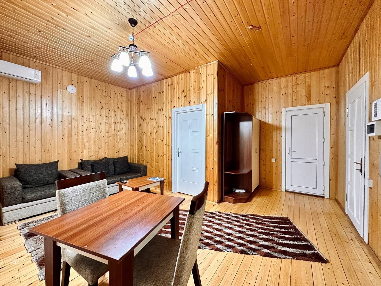 A wooden-paneled room with a dining table, sofa, and a television.