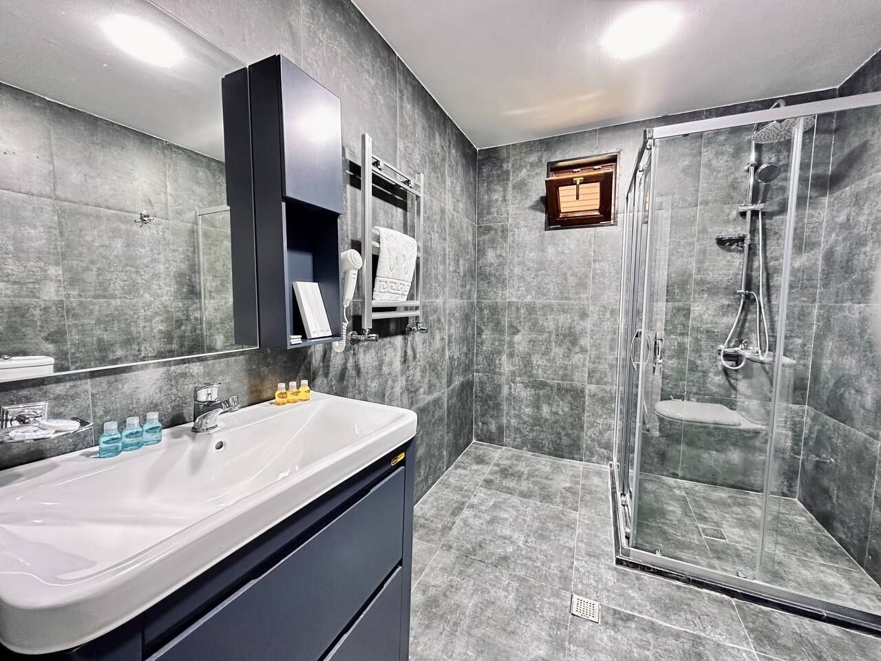 A modern bathroom with a large sink, mirror, and shower area.