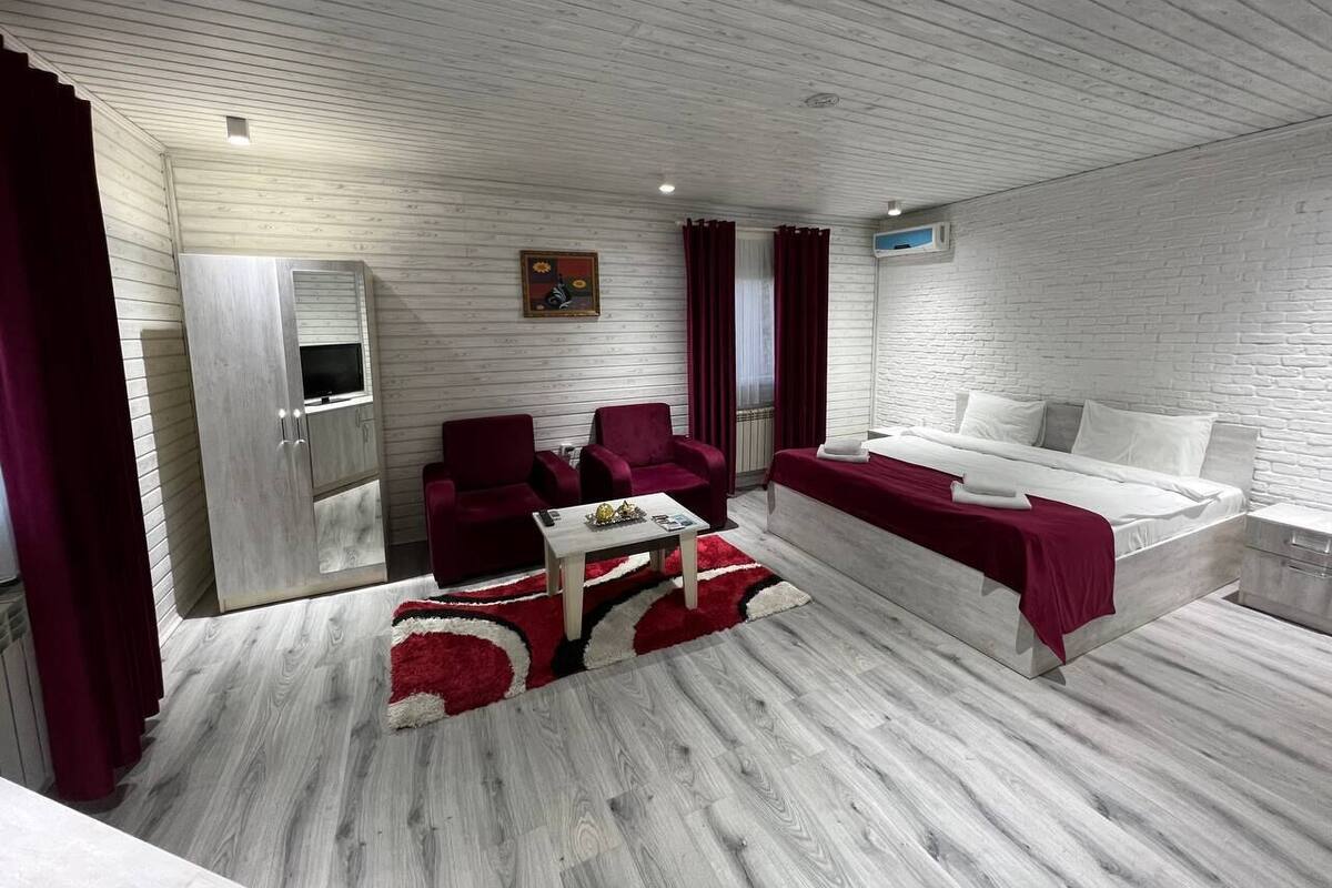 A modern room with a bed, a sofa, a TV, and a wardrobe.