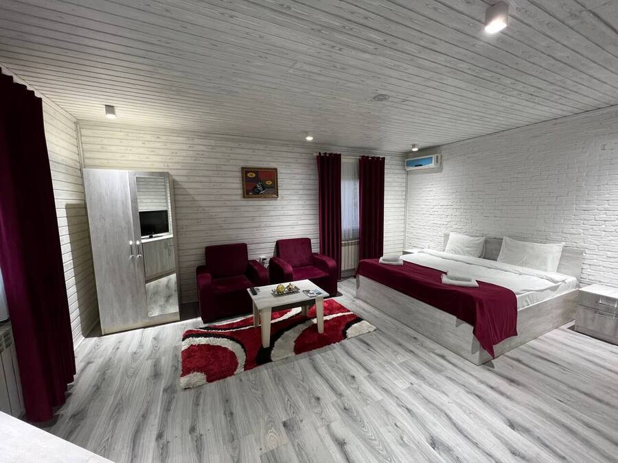 Een moderne kamer met een bed, een bank, een televisie en een kledingkast.