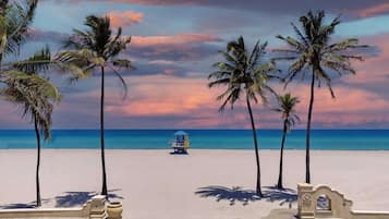 A beach with palm trees, a lifeguard tower, and a clear sky.