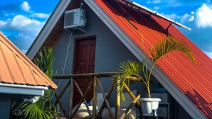 A house with a red roof, a wooden door, and an air conditioning unit. - Home Villa Eco Boutique (Arusha)