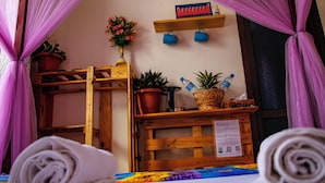 A room with a wooden bed, a small wooden shelf with potted plants, a bottle, and a sign on the wall. - Home Villa Eco Boutique (Arusha)