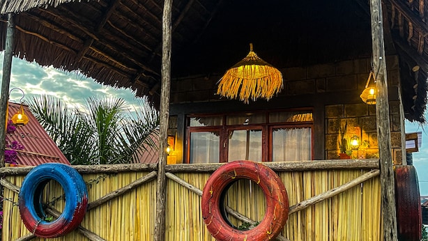 A rustic building with a thatched roof, wooden walls, and a hanging light fixture. - Home Villa Eco Boutique (Arusha)