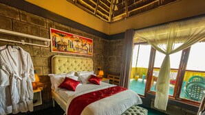 A bedroom with a large bed, a bench, a robe rack, and a painting on the wall. - Home Villa Eco Boutique (Arusha)