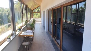 A balcony with a wooden floor, a table with chairs, and potted plants. - Ecological House (Suite Room) (Angra do Heroísmo)