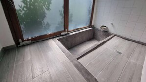 A bathroom with a shower area, a window with frosted glass, and a tiled wall. - Ecological House (Suite Room) (Angra do Heroísmo)