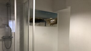 Een badkamer met een douchecabine van glas, een toilet en een handdoekhouder aan de muur.