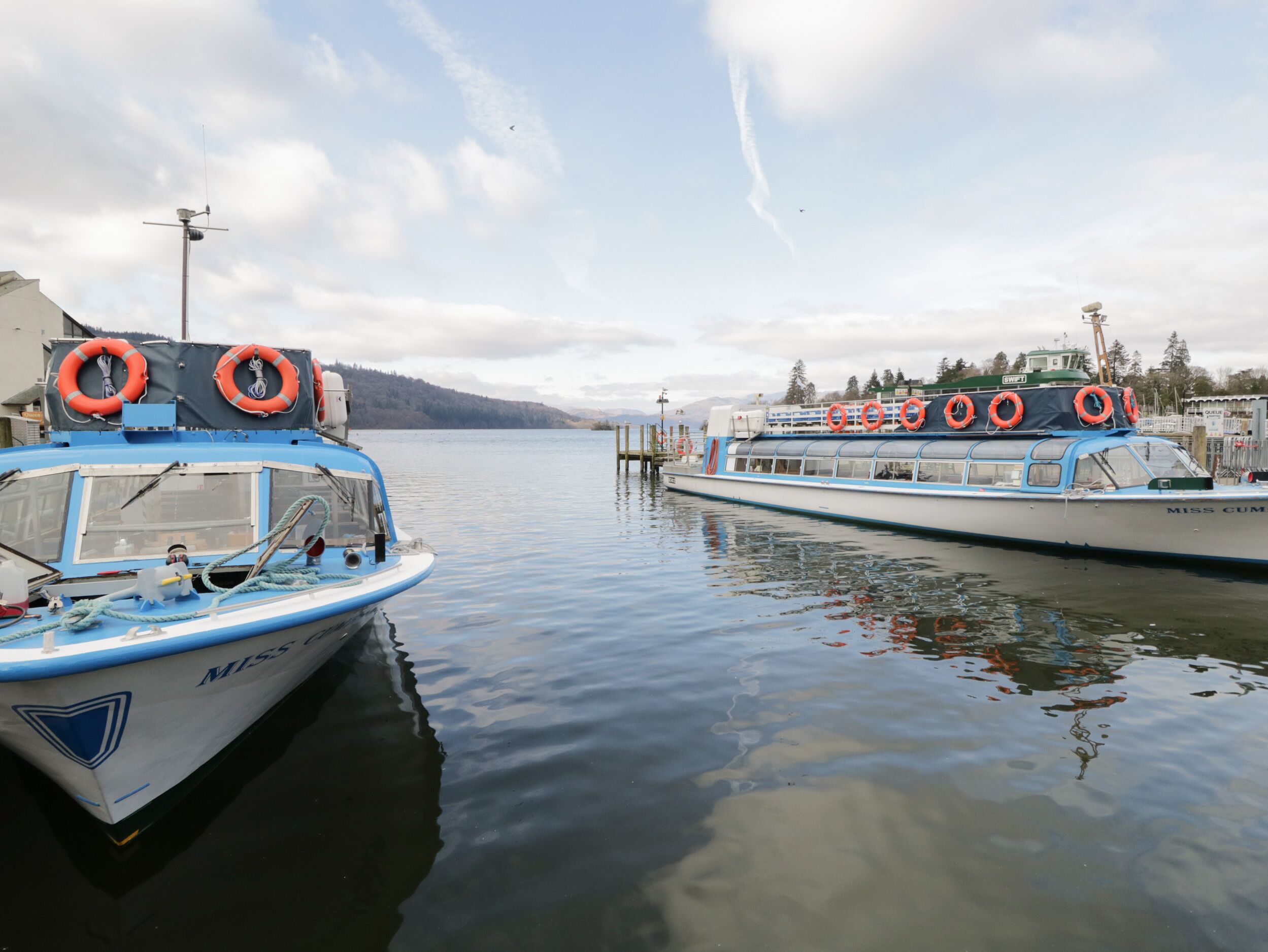 Zwei Boote liegen an einem Steg, auf dem Rettungsringe liegen.