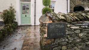Un muro de piedra con un letrero que dice "Oak Cottage Elm Grove".