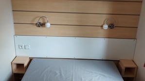 Un dormitorio con cabecera de madera, colchón blanco y dos mesitas de noche.