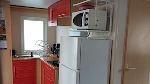 Una cocina compacta con microondas, refrigerador y armarios de madera.